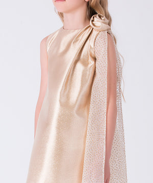 Close-up of draped shoulder detail with floral accent and sheer dotted tulle on gold girls occasion dress.