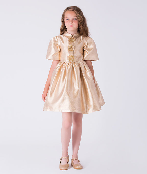 Front view of golden satin girls dress with floral brooch embellishments and structured A-line skirt from Golden Amara collection.