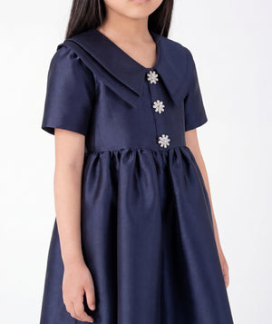 Close-up of Enchanting Brooch Girls Dress in navy satin for girls ages 3 to 12, highlighting fabric texture and designer details