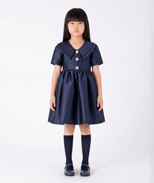 Front view of Enchanting Brooch Girls Dress in navy satin for girls ages 3 to 12, a premium children’s design by Mama Luma