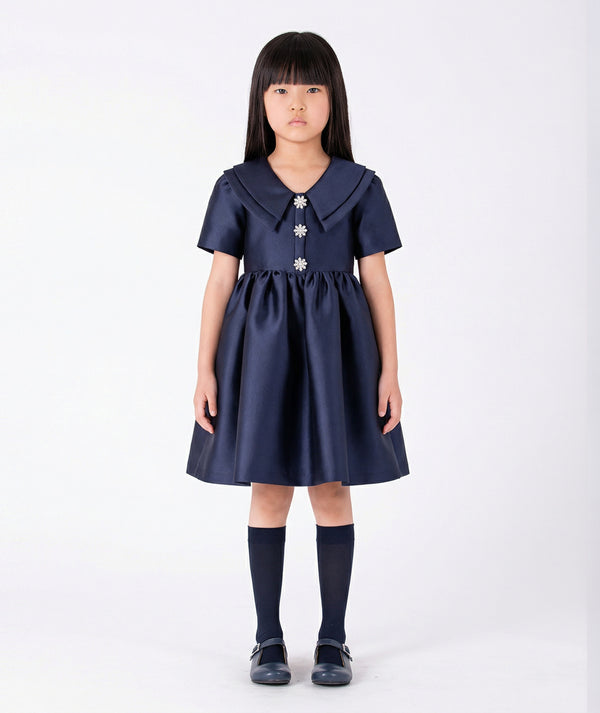 Front view of Enchanting Brooch Girls Dress in navy satin for girls ages 3 to 12, a premium children’s design by Mama Luma