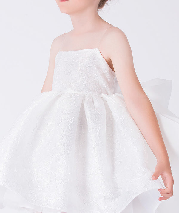 Close-up of textured jacquard fabric on an exquisite girls occasion dress, worn by a 7-year-old girl, highlighting refined structure and elegant volume.