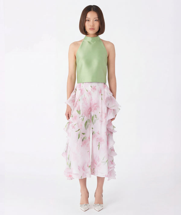 Woman wearing a light green top and pink floral skirt on a white background