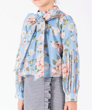 Close-up of luxury girls floral blouse featuring an oversized self-tie bow, rose motif and structured sleeve cuffs