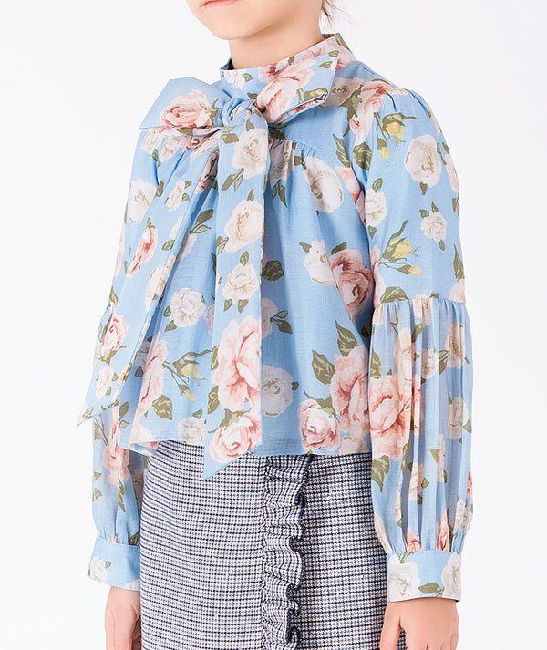 Close-up of luxury girls floral blouse featuring an oversized self-tie bow, rose motif and structured sleeve cuffs
