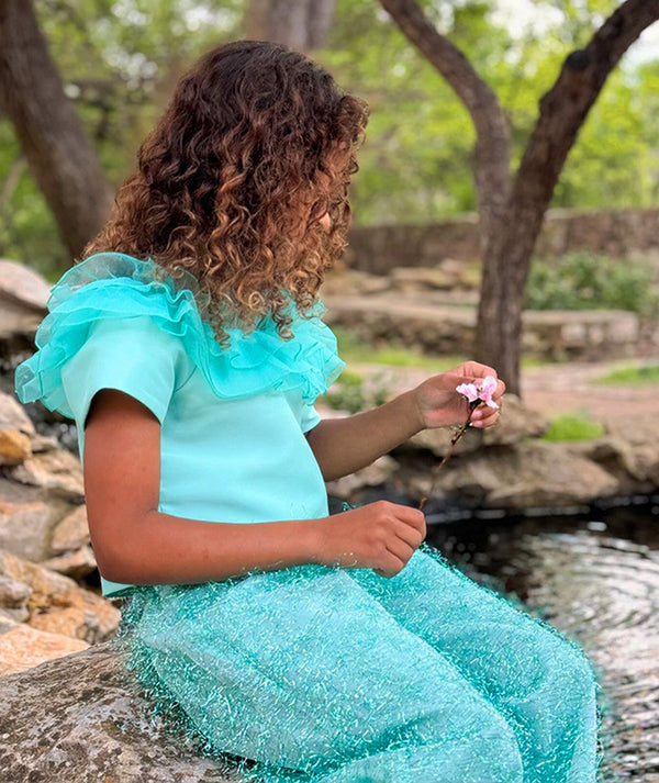 blue ruffled blouse and shimmering feathered pants