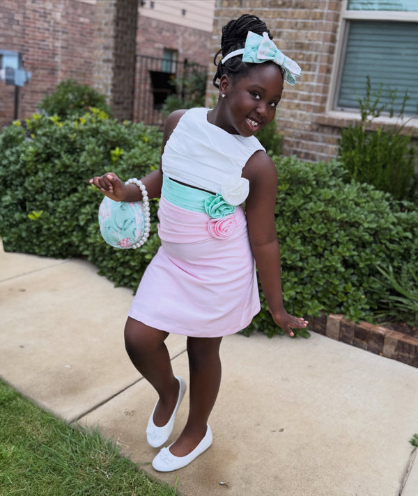 Girl wearing a mint floral top and pink skirt outdoors