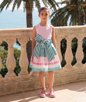 Girl wearing a pink striped bow dress beside the sea