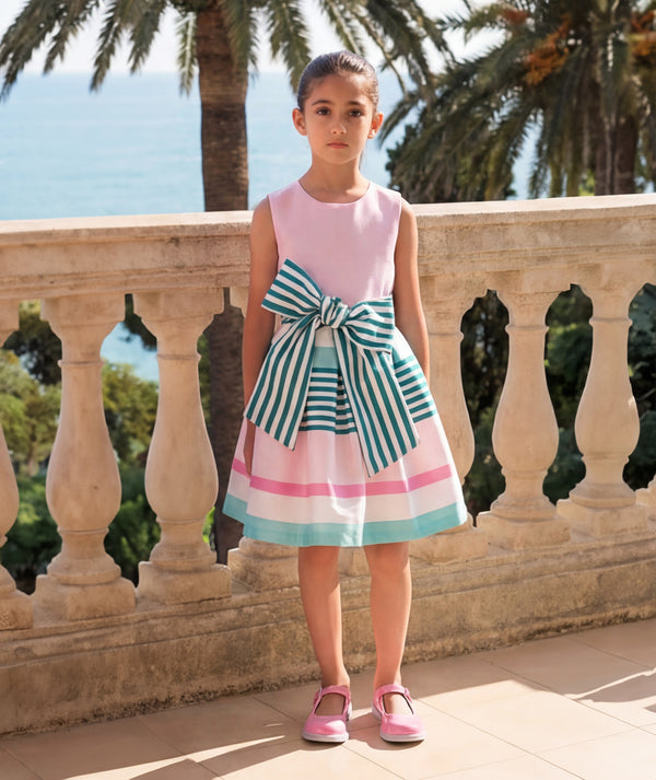 Girl wearing a pink striped bow dress beside the sea