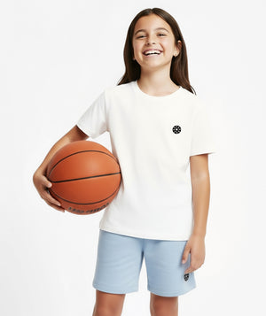 GoldenCubs girl smiling in a white logo T-shirt and light blue shorts, styled for sporty comfort and casual everyday wear. Available in sizes 3–12Y.