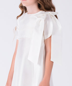 Close-up of statement shoulder bow and flowing sash on ivory formal girls ceremony dress.