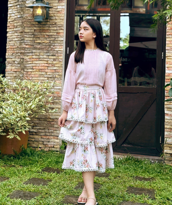 Charming girls’ outfit by Mama Luma — pastel pink blouse with puff sleeves and floral tiered skirt, perfect for garden parties, birthdays, and weddings