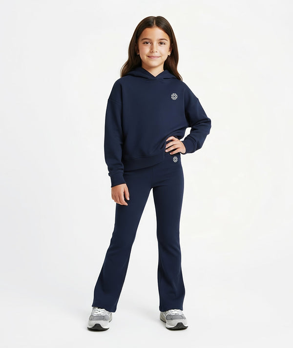 Front-facing lifestyle image of a girl wearing a navy hoodie with coordinating flared pants, styled for polished school outfits, everyday confidence, and comfortable movement, available in sizes 3–14