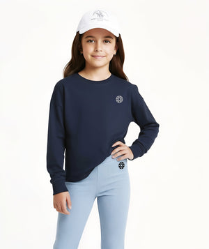 Front-facing lifestyle image of a girl wearing a navy long sleeve sweatshirt with light blue ribbed pants and a cap, styled for sporty everyday outfits, school-ready comfort, and relaxed movement, available in sizes 3–14