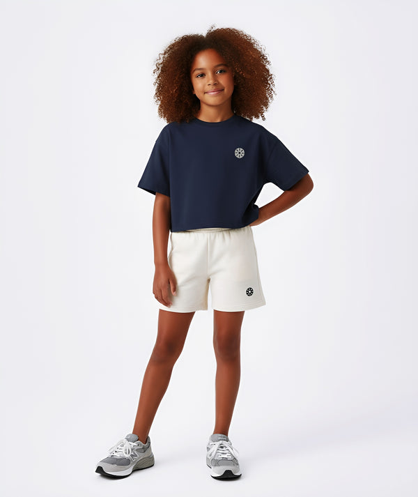 Girl wearing a navy short sleeve sweatshirt and white shorts, styled for everyday athleisure, school days, and active play, available in sizes 3–14