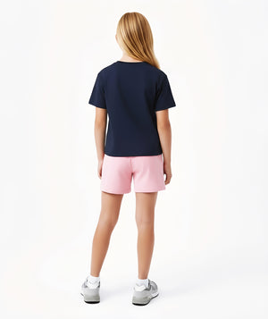 Girl seen from the back wearing a navy short sleeve t-shirt and pink shorts, styled for everyday athleisure, school days, and active play, available in sizes 3–14