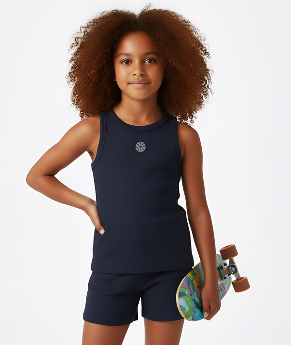 Front-facing lifestyle image of a girl wearing a navy sleeveless tank top with matching shorts while holding a skateboard, styled for urban play, warm-weather activity, and confident everyday wear, available in sizes 3–14
