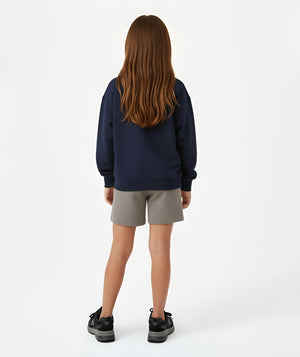 Girl seen from the back wearing a navy sweatshirt and taupe shorts, styled for everyday athleisure, school days, and active play, available in sizes 3–14