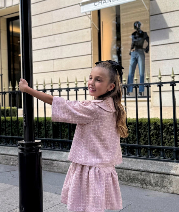 Girl in Mama Luma pastel pink tweed jacket and skirt set with bow detail — chic girls’ party outfit and luxury occasionwear, perfect for city celebrations and birthdays