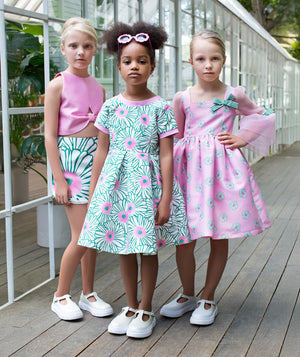 Girls pastel pink and green dresses featuring floral prints, bows, and modern silhouettes, styled for birthday celebrations, family gatherings, garden parties, and stylish spring occasions, available in sizes 3–12
