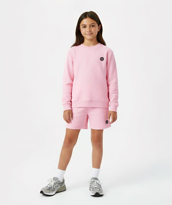 Girl wearing a pink sweatshirt and matching pink shorts, styled for everyday athleisure, school days, and active play, available in sizes 3–14