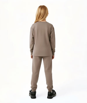 Girl seen from the back wearing a taupe long sleeve top and matching pants, styled for everyday athleisure, school days, and active play, available in sizes 3–14
