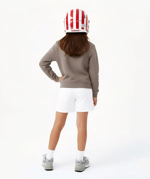 Girl seen from the back wearing a taupe sweatshirt and white shorts with a sports helmet, styled for active play, sports-inspired athleisure, and everyday wear, available in sizes 3–14