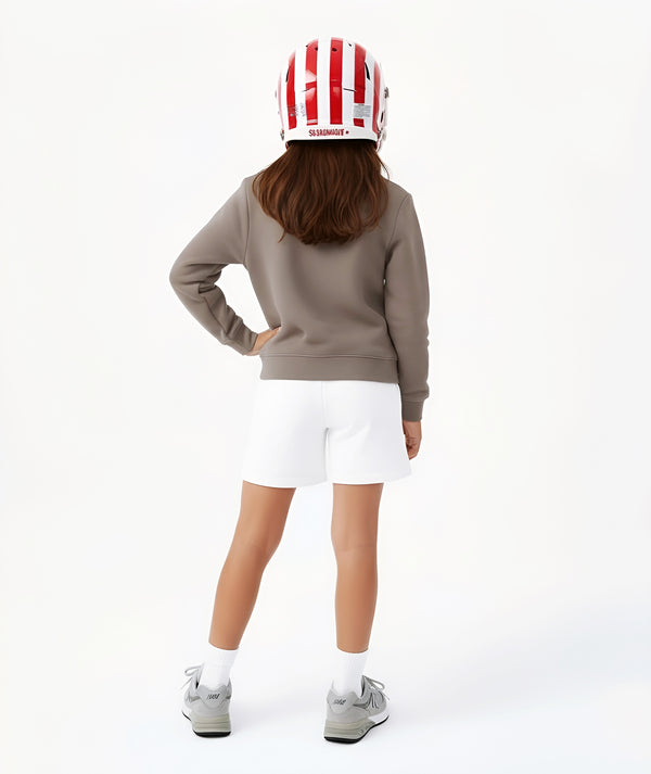 Girl seen from the back wearing a taupe sweatshirt and white shorts with a sports helmet, styled for active play, sports-inspired athleisure, and everyday wear, available in sizes 3–14
