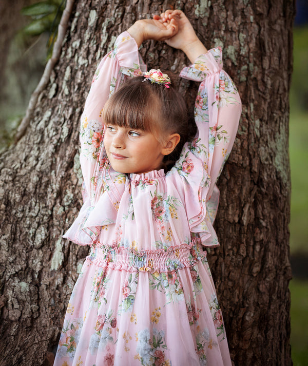 Girl in Mama Luma pink floral chiffon dress with ruffle sleeves and smocked waist — luxury girls’ wedding dress, flower girl outfit, and elegant partywear