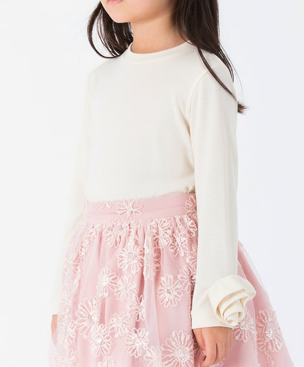 Close-up of a white girls' blouse showing the intricate 3D fabric rose (rosette) on the sleeve cuff and the high-quality cotton fabric texture.