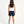 Carica l'immagine nel visualizzatore Galleria, Back-view lifestyle image of a girl wearing a white sleeveless tank top with navy shorts, styled for warm-weather movement, casual play, and everyday summer comfort, available in sizes 3–14
