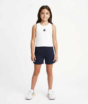 Front-facing lifestyle image of a girl wearing a white sleeveless tank top with navy shorts, styled for warm days, easy movement, and casual everyday outfits, available in sizes 3–14