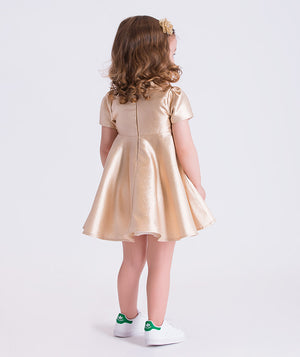 Back view of metallic gold baby girls dress featuring short sleeves, flared silhouette and concealed zipper detail