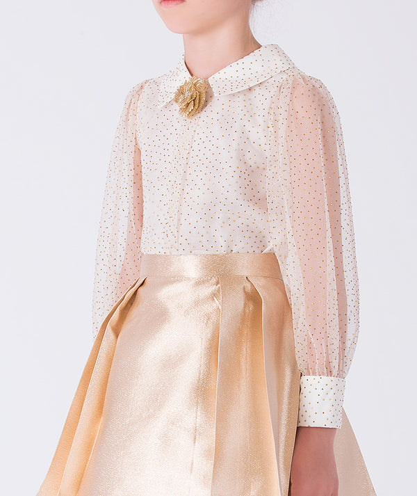 Close-up of gold girls outfit with sheer polka dot blouse, pointed collar and floral brooch detail