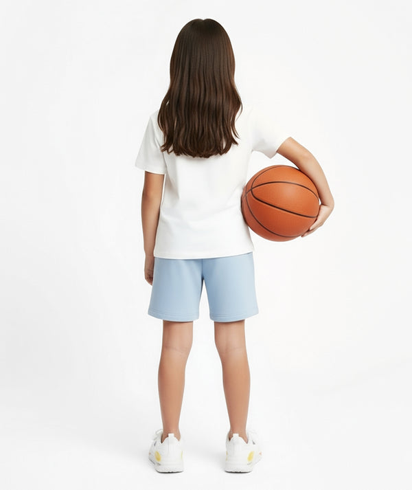 GoldenCubs girl wearing a white T-shirt and light blue shorts, holding a basketball, styled in a sporty and minimal athleisure outfit perfect for playtime or casual days. Available in sizes 3–12Y.