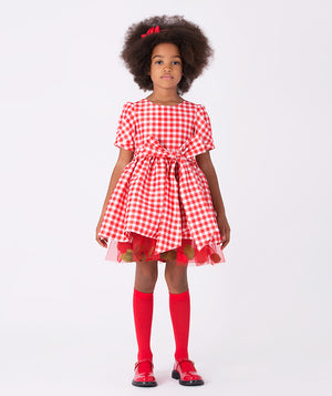 Girl wearing Mama Luma’s 3D Petals Plaid Dress in red-and-white checks with a bow and petal trim — perfect for Christmas parties, winter birthdays, and holiday photos. Available in girls’ sizes 3–12 Y.