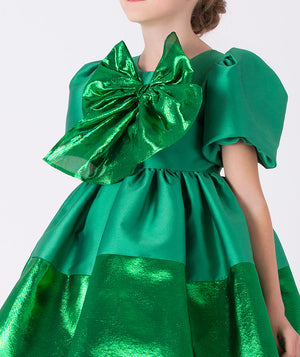 Festive emerald metallic girls’ dress by Mama Luma with statement bow and puff sleeves, ideal for Christmas celebrations, holiday portraits, and special occasions. Available in sizes 3–12 Y.