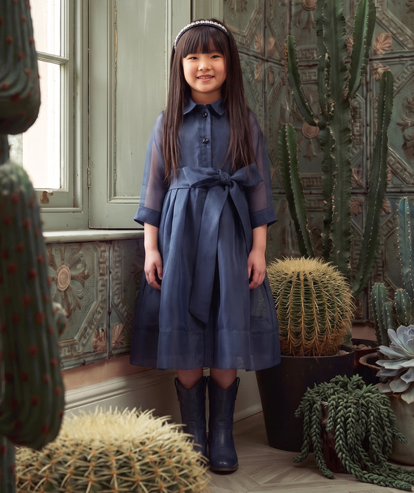 Mama Luma navy women’s special occasion dress styled in an editorial setting with a refined full-length silhouette.