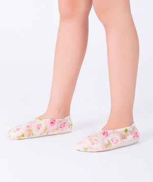 Girl wearing light pink floral swim shoes by Mama Luma, featuring delicate rose prints on a cream background. Slip-on design perfect for poolside, beach days, and summer vacations.