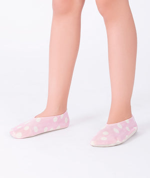 Girl wearing light pink polka-dot swim shoes by Mama Luma. Soft slip-on design with white polka dots, perfect for poolside, beach days, and summer vacations.