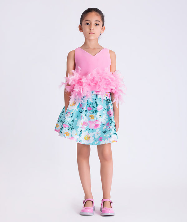 Girl wearing Mama Luma Kohana Feathers two-piece outfit with pink feather top and floral skirt, front view.
