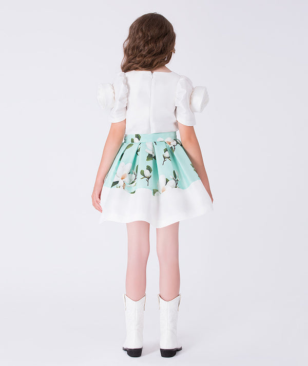 Back view of a mint green floral girls outfit featuring a short sleeve top with puff sleeves and a matching skirt with contrast hem, styled for birthdays, weddings, garden parties, and special occasions, available in sizes 3–12