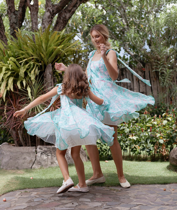 Mother and daughter twirling in matching mint floral dresses