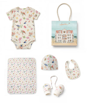 Collection of baby items including a onesie, blanket, teether, and more on a white background.
