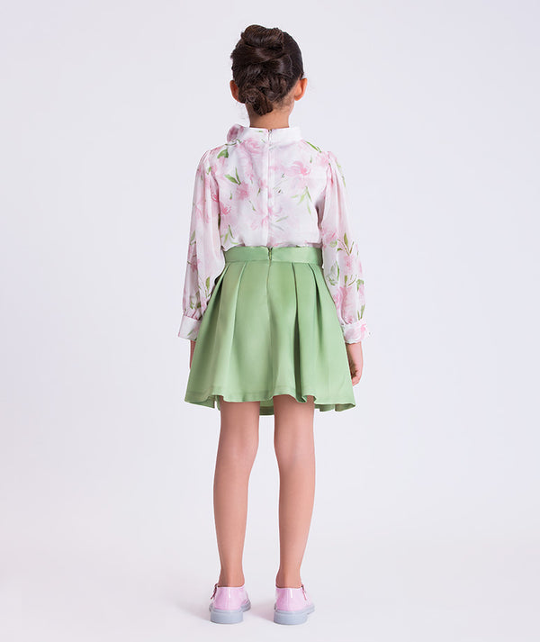 Back view of a two-piece girls outfit with floral blouse and pleated skirt, designed for family celebrations and polished daytime events.