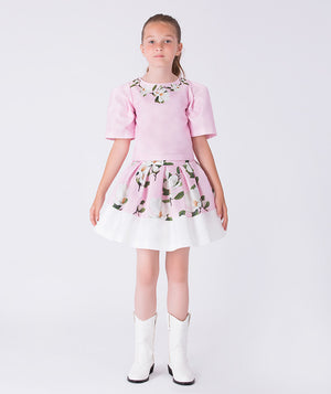 Front view of a pink floral girls occasion outfit featuring a short sleeve structured top and a matching flared skirt with contrast hem, styled for birthdays, weddings, garden parties, and special occasions, available in sizes 3–12