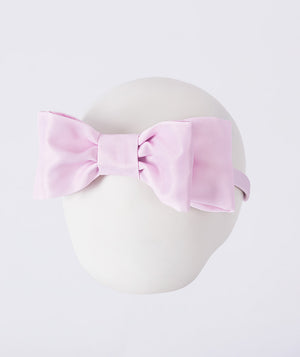 Pink satin bow headband for girls by Mama Luma, styled as an elegant hair accessory for weddings, celebrations, and special occasions.