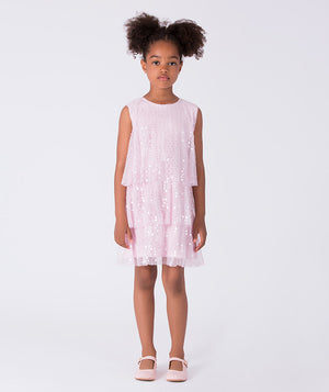 5 years old girl wearing a light pink dress with white polka dots on a white background