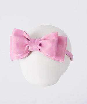 Pink bow headband on a mannequin head with a white background
