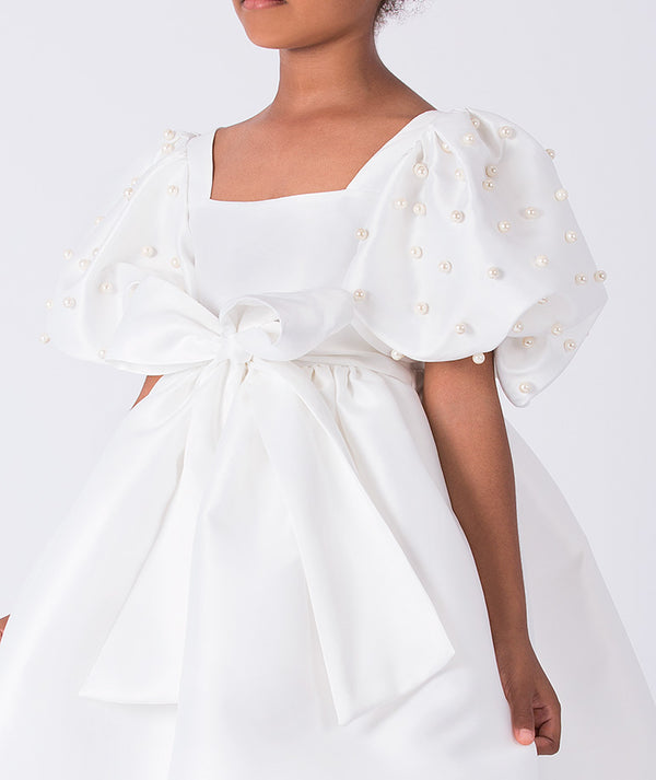 Close-up of pearl embellished puff sleeve on ivory girls occasion dress with structured bodice.